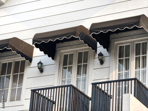 Canvas Print Close up of black canvas awnings over french windows and balconies on white house facade, outdoor window canopies, real estate detail, and exterior decor