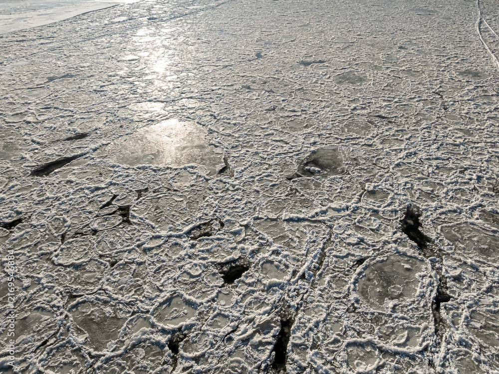 Fototapeta premium Ice floe drifting on frozen Brda River at sunrise.