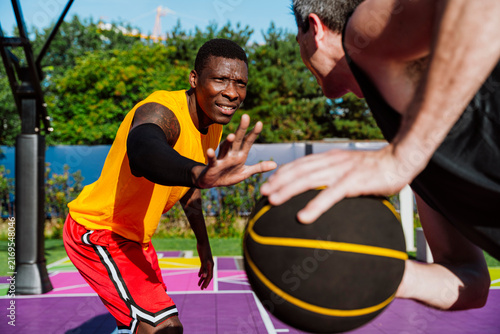 A male athlete defends his opponent during an outdoor streetball game