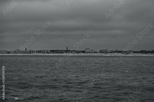 Dramatic dark seascape with choppy ocean waves and distant coastline under a heavy stormy sky. Moody atmospheric weather and powerful nature background.