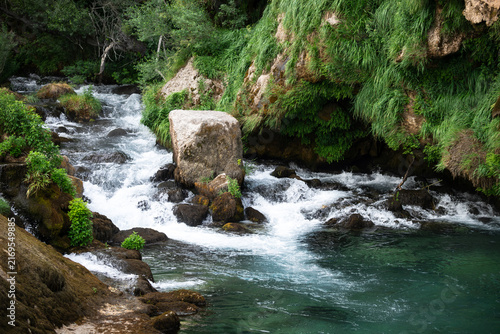Фотография Beautiful turquoise water basin at the natural source of Krka river under a rocky cliff