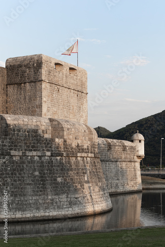 Fotografía Ancient medieval stone fortress Kaštio and defensive walls reflecting in a calm water canal at dusk