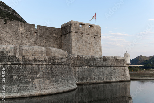 Canvas Print Ancient medieval stone fortress Kaštio and defensive walls reflecting in a calm water canal at dusk