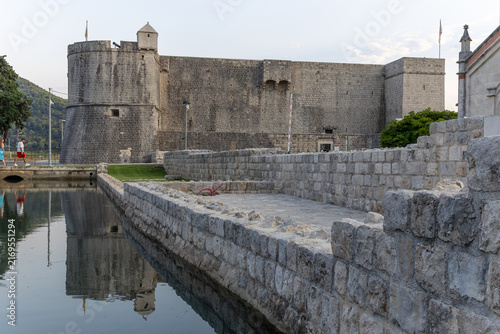 Canvas Print Ancient medieval stone fortress Kaštio and defensive walls reflecting in a calm water canal at dusk