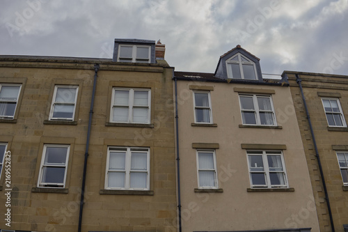 Canvastavla Exterior facade of adjacent residential buildings showing stone and rendered walls with windows and roof dormers against cloudy sky