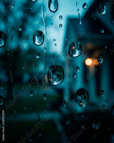 Foto Rain droplets on glass with blurred blue city lights create a cinematic moody background, ideal for weather, urban lifestyle, melancholy concepts, music artwork and atmospheric design