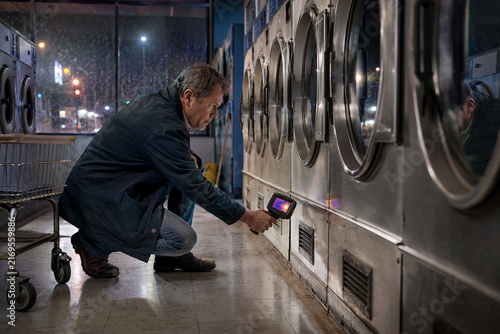Laundromat owner checking dryers with a thermal camera