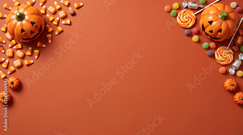 Halloween flat lay border with pumpkins and candy on orange background
