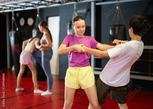 Fotografie Purposeful engrossed teen boy and girl train during self-defense fight training session and work out basic elements with partner