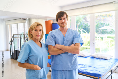 Physiotherapists In Rehab Center Man And Woman Wearing Blue Scrubs Rehabilitation After Injury Indoor Physical Therapy Setting Healthcare