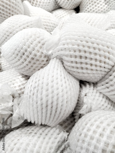 Fresh fruits wrapped in white protective foam mesh netting on display at a retail store, ideal concept for fresh produce packaging, transport, and logistics.