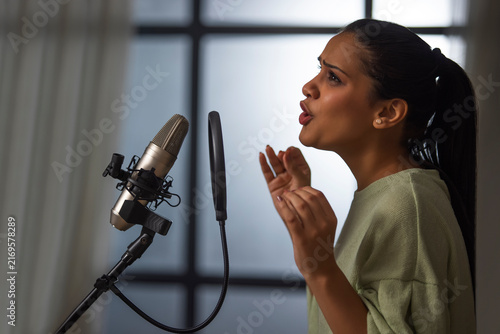 A YOUNG PROFESSIONAL SINGER RECORDING MUSIC ON MICROPHONE