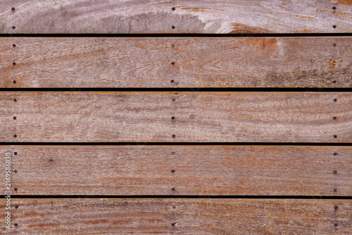Weathered horizontal wooden planks with natural wood grain and rows of screw heads. Abstract brown background