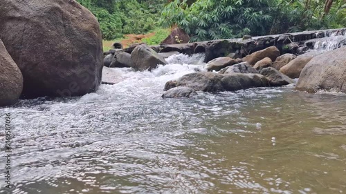 Serene Stream Cascading Over Stones Surrounded By Vibrant Greenery In A Peaceful Forest Environment