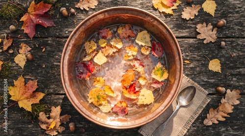 Copper bowl filled with water and floating autumn leaves