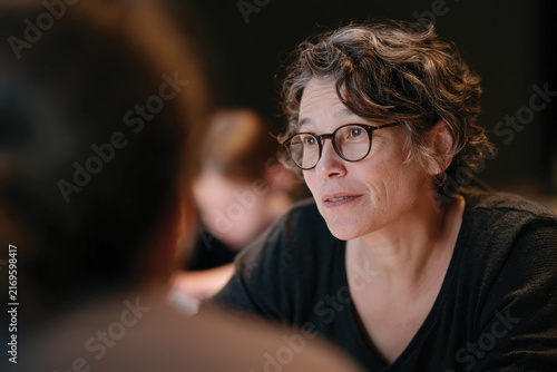 A thoughtful woman participates in an intense conversation, exemplifying the depth of interpersonal communications and the importance of empathy in understanding differing perspectives.