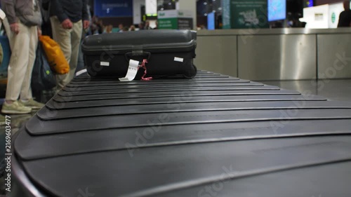Baggage conveyor at an airport is moving suitcases, people are waiting, 4k