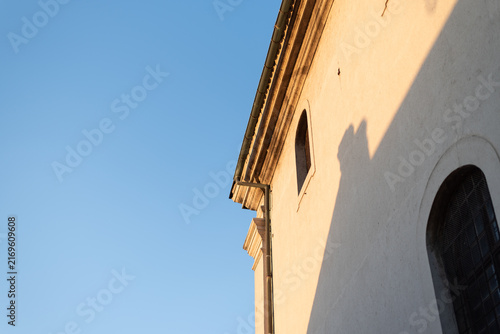 Low-angle shot of historical church facade illuminated by warm golden hour sunlight. Petrovaradin, Serbia