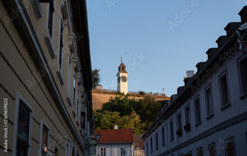 Historic Petrovardin Fortress clock tower stands on hill framed by European-style city buildings. Novi Sad, Serbia