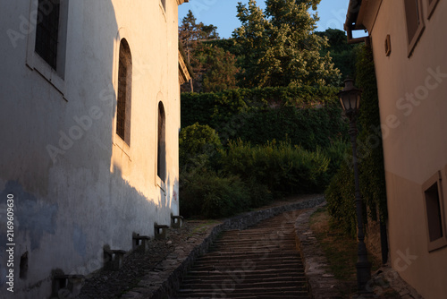 Stone staircase ascends between historical buildings during the warm golden hour. Petrovaradin, Serbia