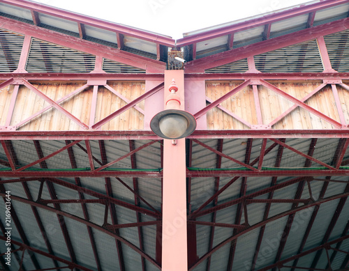 Symmetrical architectural detail of industrial steel canopy roof with vintage lamp and wooden panels. abstract layout for construction engineering article, retro loft design banner or texture pattern