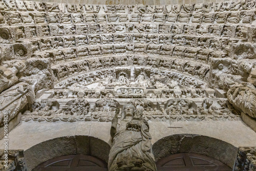 An ornate gothic stone portal features intricate sculptural reliefs and religious figures