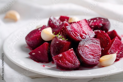 Healthy roasted beetroot salad chunks with garlic cloves on white plate. Great food imagery for vegetarian restaurant menu design, nutrition blog post, fitness recipe layout or grocery store banner