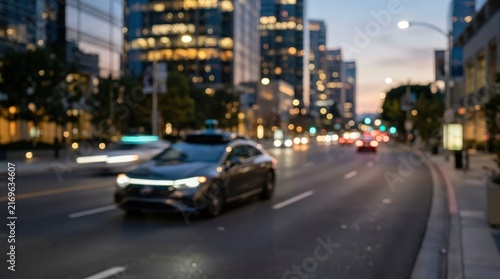 Autonomous vehicle driving on a city street at twilight. The car features roof-mounted sensor equipment while moving through an urban environment with blurred city lights.
