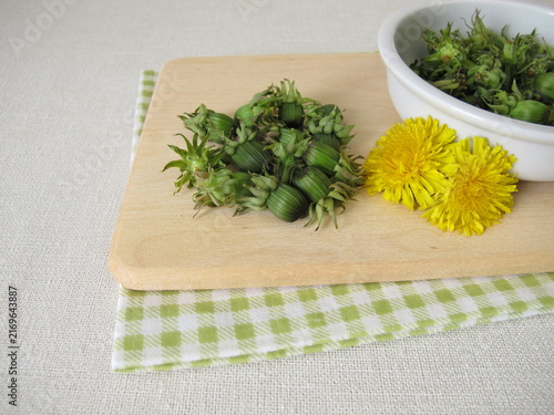 Fresh dandelion buds from the meadow on a wooden cutting board