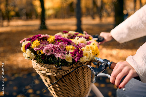 Quadro su tela Colorful flower basket on a bicycle in an autumn park.