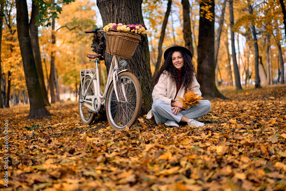Fototapeta premium Smiling woman with bicycle in autumn park.