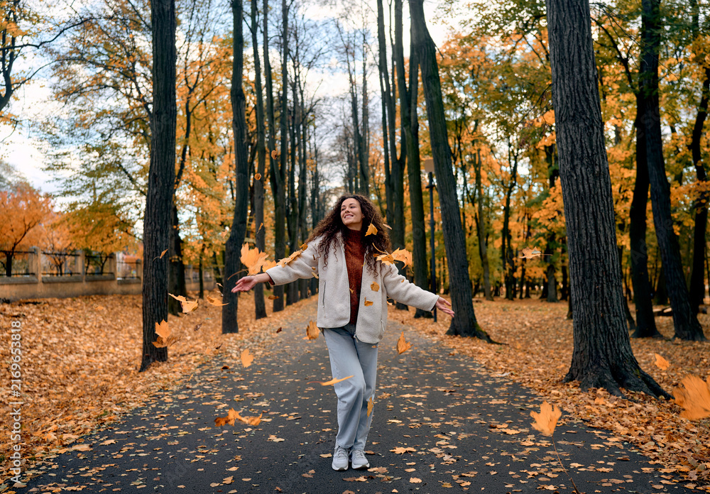 Fototapeta premium Smiling woman enjoying an autumn walk in the park.