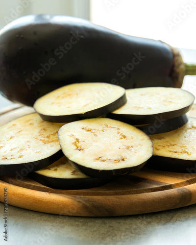 Fresh Eggplant Slices on Wooden Cutting Board Close Up