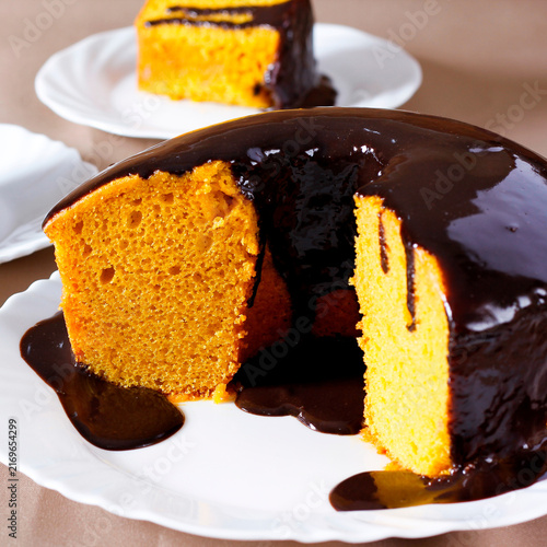 Brazilian carrot cake with a glossy chocolate glaze on a white plate.