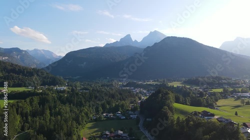 Aerial drone view of the iconic Watzmann mountain near Schönau am Königssee in Bavaria, Germany, featuring its distinctive twin peaks illuminated by warm sunset light. Slow, smooth cinematic footage