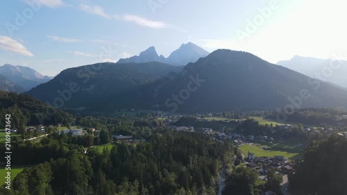 Aerial drone view of the iconic Watzmann mountain near Schönau am Königssee in Bavaria, Germany, featuring its distinctive twin peaks illuminated by warm sunset light. Slow, relaxing cinematic footage