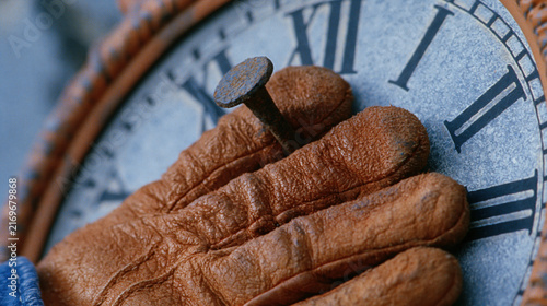 Weathered leather glove nailed to a vintage clock at quitting time