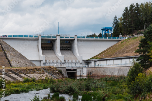Bild auf Leinwand Large concrete hydroelectric dam and spillway designed for water regulation, with a downstream channel flowing through a green landscape