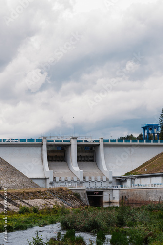 Obraz na płótnie Large concrete hydroelectric dam with multiple spillway gates and a downstream water channel, illustrating modern water management and civil engineering infrastructure