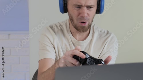 man wearing beige shirt playing video game with headphones in casual indoor setting focused and engaged close-up slightly angled view plastic cloth shirt gaming entertainment.