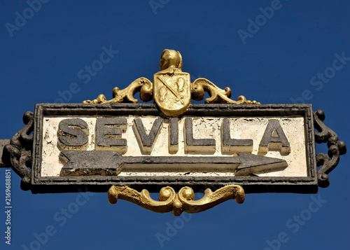 Sevilla street sign with ornate golden heraldry pointing direction. Spain - Sevilla