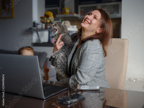 Mother working remotely from home, caucasian woman with her cat using laptop at home. Smart working and smart studying with pet