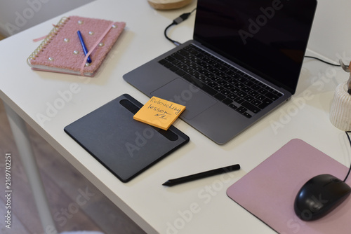 Top-down view of workspace with laptop, graphics tablet and sticky note with 