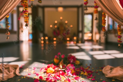 Ritual diya lamp and scattered flower petals on a polished floor in a decorated ceremonial hall for Navratri and festive decor campaigns