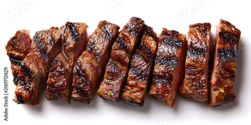 Sliced grilled beef steak arranged in a row on a white surface