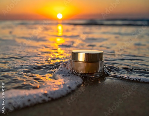 A golden jar of skincare sits on a sandy beach, kissed by the gentle waves and illuminated by the warm, radiant glow of the setting sun.
