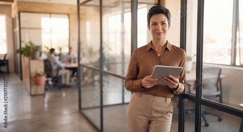 Professional woman with tablet standing in modern office