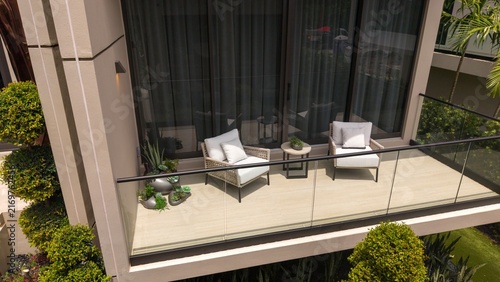 Modern luxury apartment or house balcony featuring outdoor woven armchairs, a glass railing, and a view of landscaped greenery