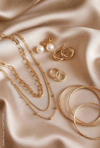 Luxury Gold Jewelry Flat Lay with Pearl Earrings Chains and Bangles on Champagne Satin Fabric