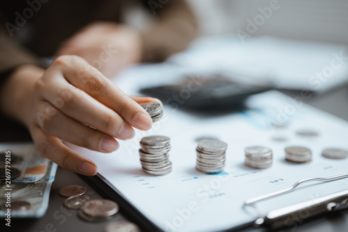 Bild auf Leinwand An accountant stacks coins beside forecast documents, using financial planning, strategy, report and risk analysis to compare growth and projection scenarios before revising the financial outlook